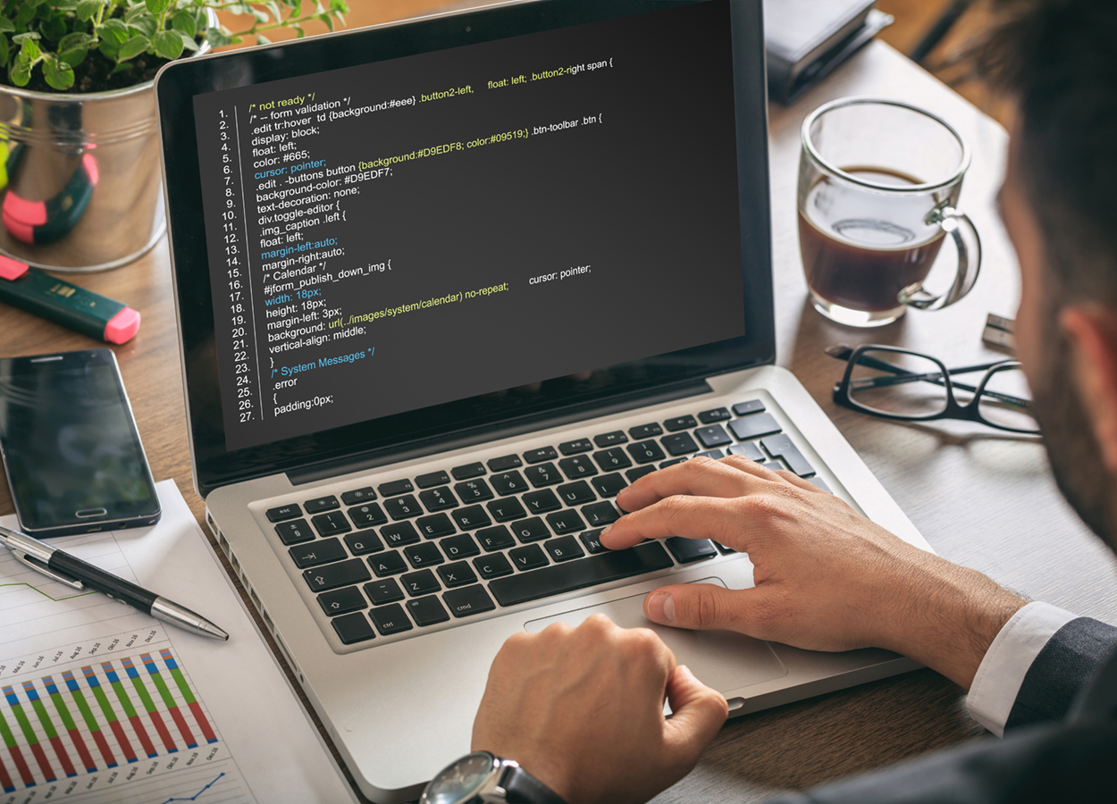 Programmer sitting down programming on their laptop.