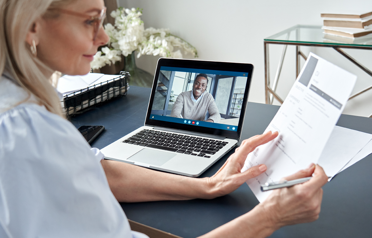 Image showing a woman sitting in front of a laptop interviewing a man virtually.