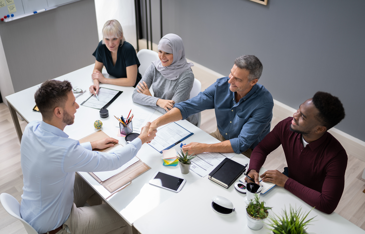 Image showing a table with multiple people interviewing one individual in person.
