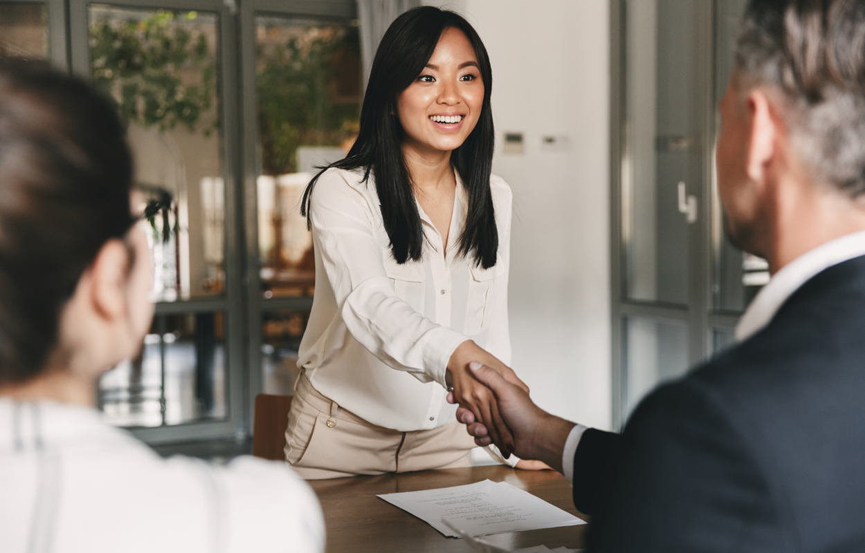 Image depicting a young woman shaking hands with two professionally-dressed people.