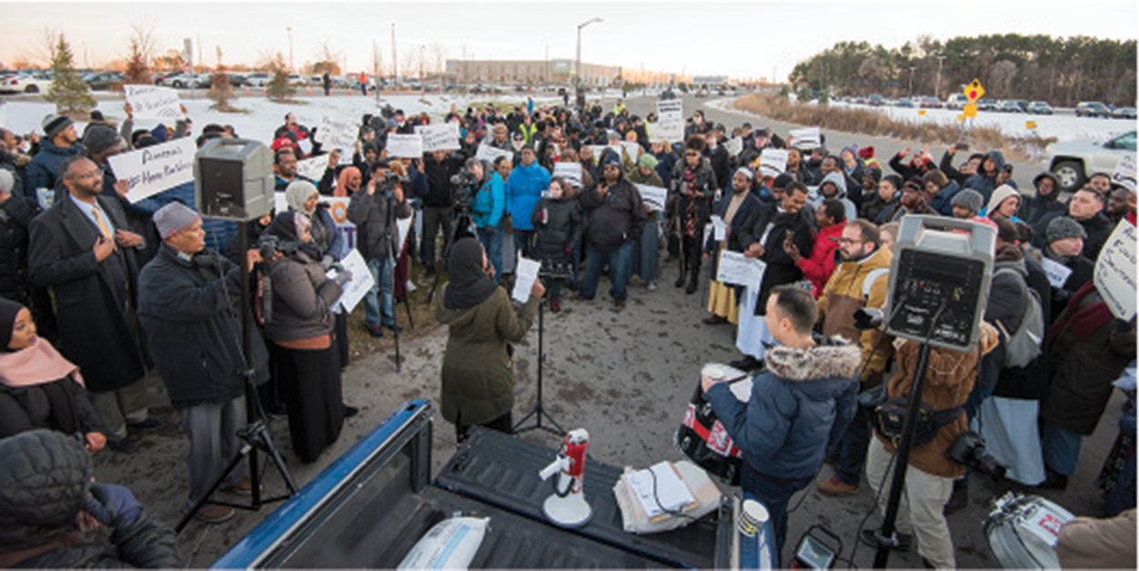 A photo of a crowd of people surrounding a speaker.