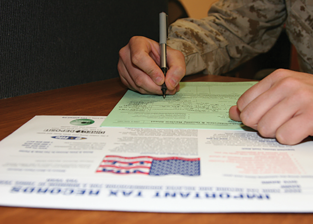 An image of a person’s hand, holding a pen over a form.