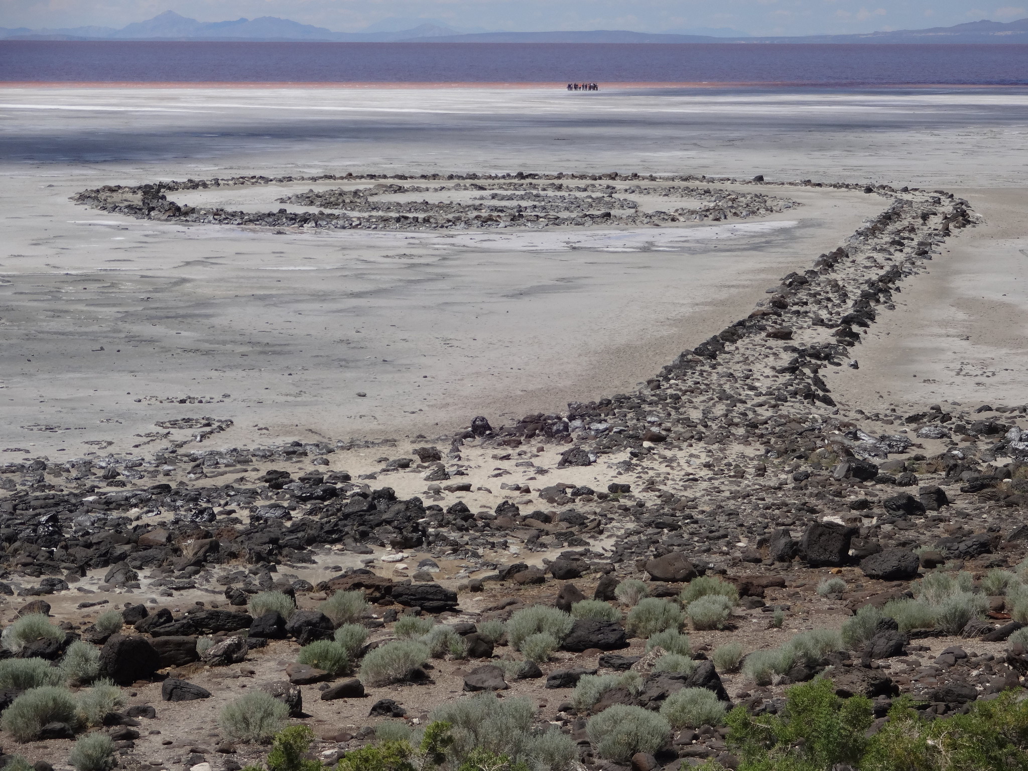 large piles of rocks forming a spiral into a lake