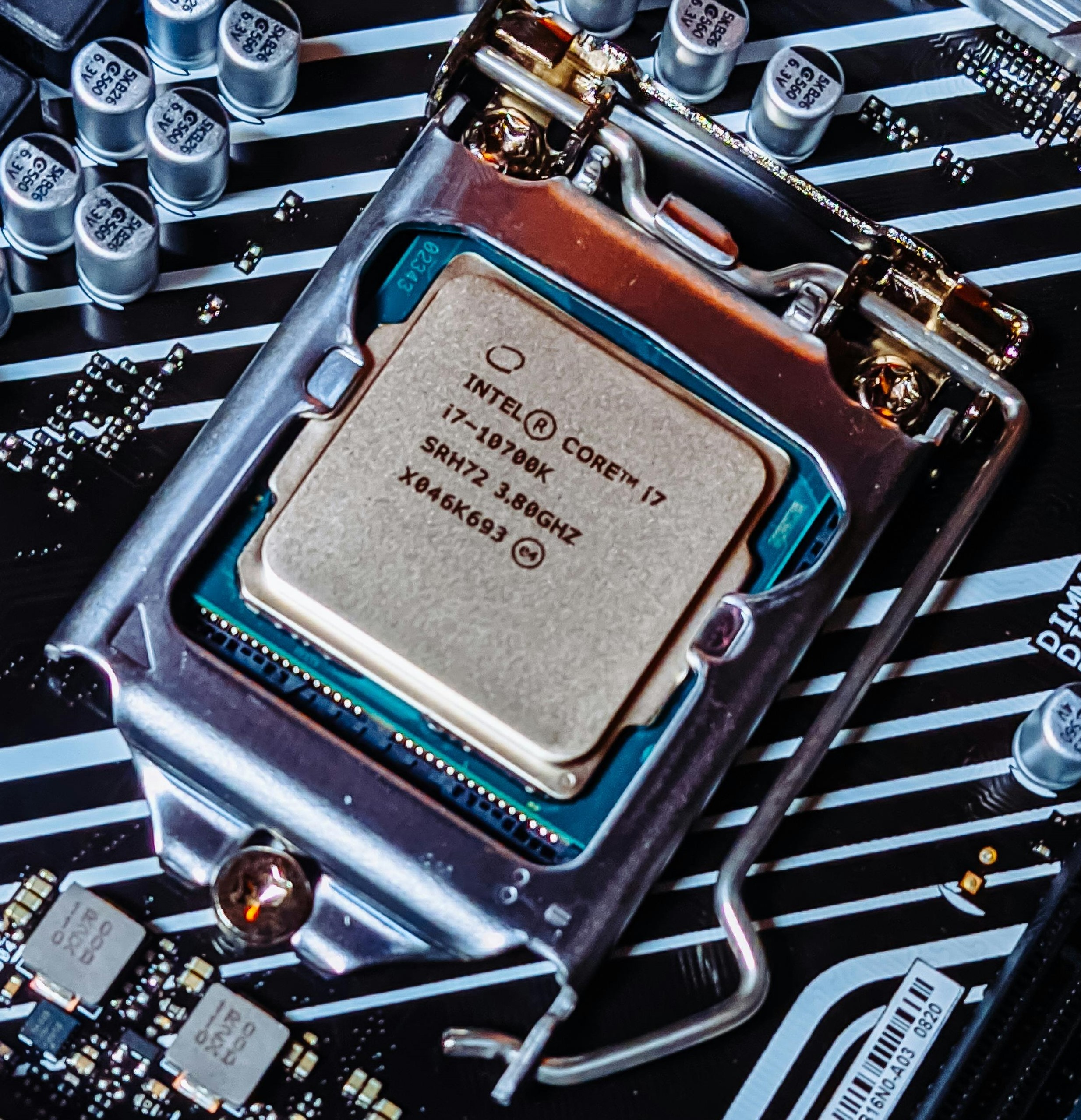 An Intel core I 7 10700K C P U with the following specifications: SRH72, 3.8 GHz, and X046k693. The C P U has been clamped to a motherboard.