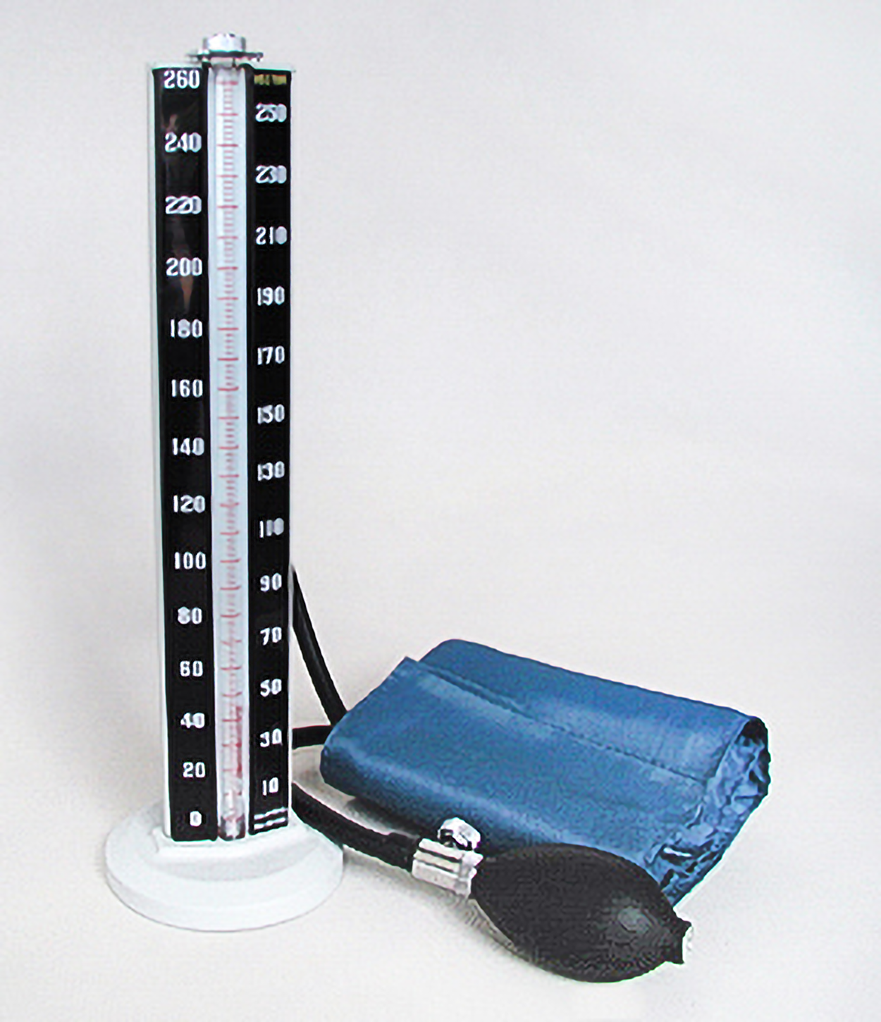 A vertical bar has a central tube with measurements to the left and right of the tube. Nearby, there is a blood pressure cuff with a bulb to inflate the cuff.